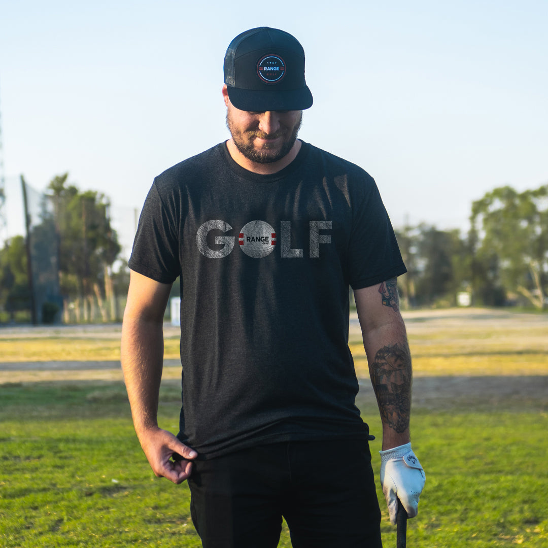 man on golf course wearing black t-shirt with range golf ball as "o" in "golf" design